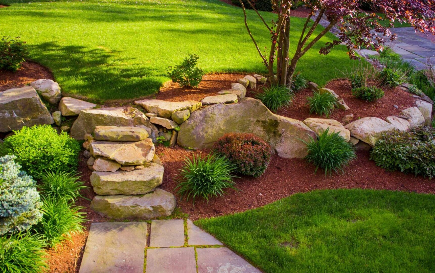 A garden with rocks and steps leading to the ground.